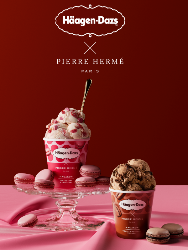 Two pints of Häagen Dazs ice cream on a pink surface surrounded by macarons